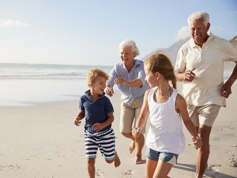Grandparents running on the beach with their grandchildren