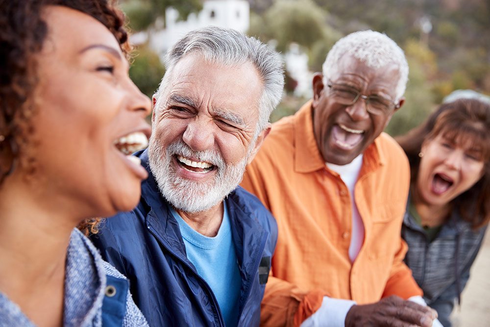A group of older friends laughing together outdoors